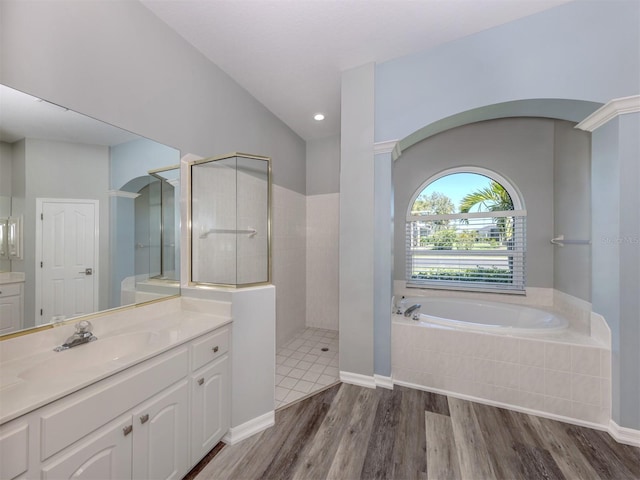 bathroom with walk in shower, wood finished floors, vanity, and a bath