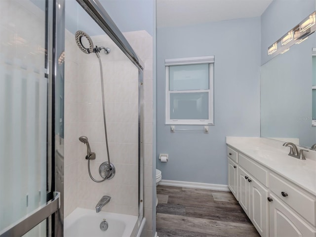 bathroom featuring vanity, wood finished floors, baseboards, shower / tub combination, and toilet