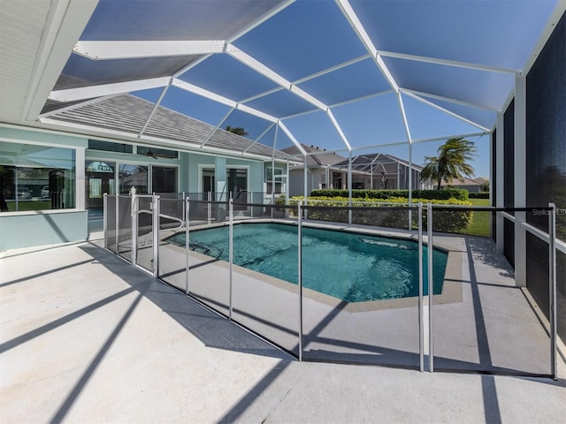 outdoor pool featuring glass enclosure and a patio