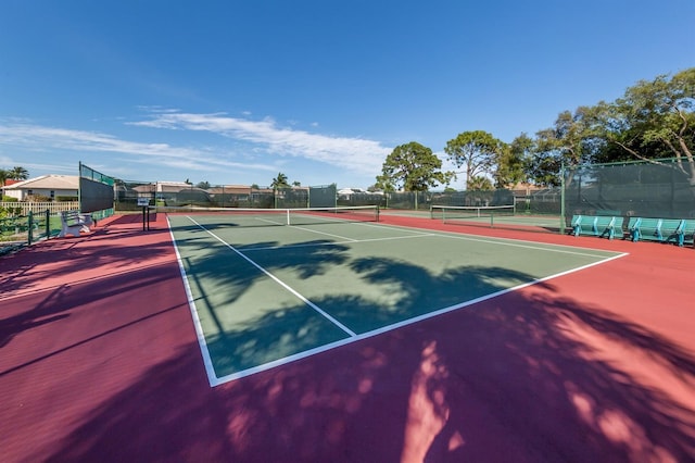 view of tennis court featuring community basketball court and fence