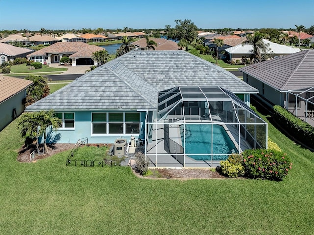 rear view of property with a residential view, glass enclosure, an outdoor pool, and a lawn