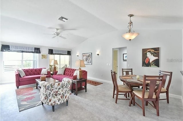 interior space with a ceiling fan, visible vents, baseboards, vaulted ceiling, and light carpet