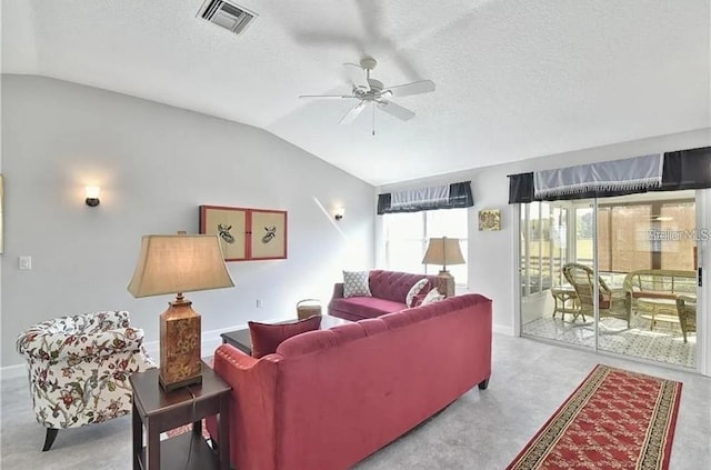 living room with vaulted ceiling, a ceiling fan, visible vents, and a textured ceiling