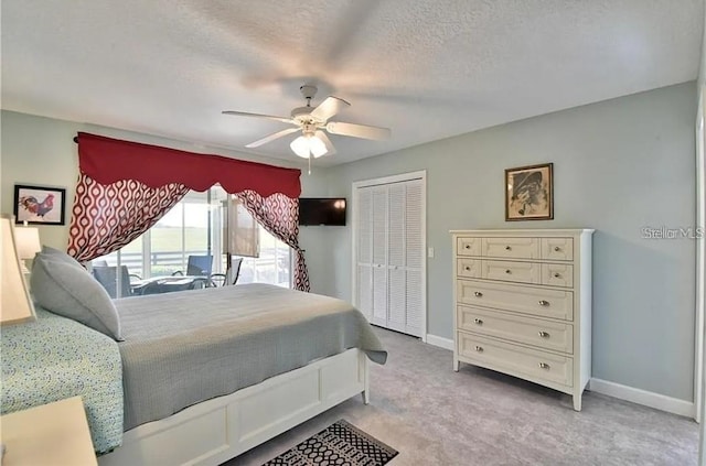 bedroom featuring baseboards, ceiling fan, carpet, a closet, and a textured ceiling