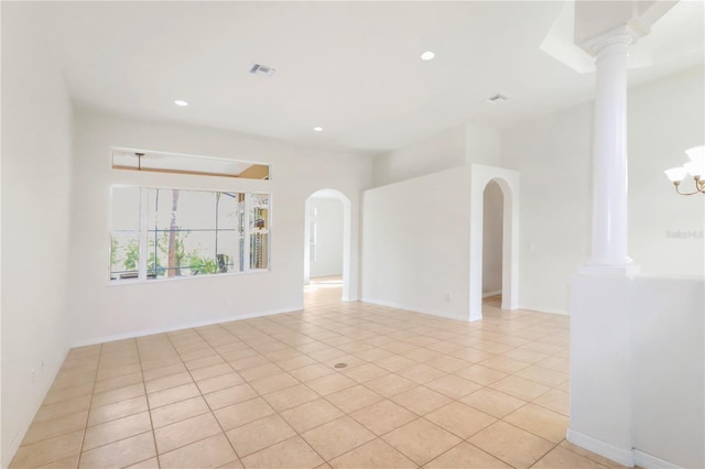 empty room with visible vents, decorative columns, recessed lighting, arched walkways, and light tile patterned flooring