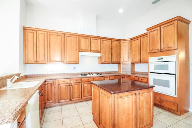 kitchen featuring light tile patterned floors, white appliances, light stone countertops, and a sink