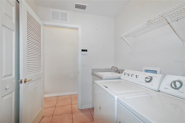 washroom with laundry area, washer and dryer, visible vents, and a sink