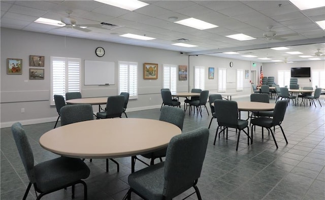 dining area with a drop ceiling, baseboards, visible vents, and a ceiling fan