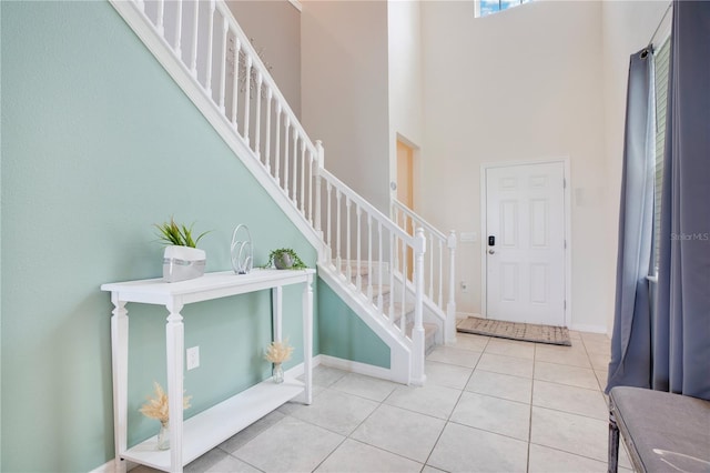 tiled entrance foyer featuring stairway, baseboards, and a high ceiling