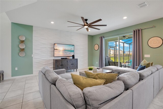 living area featuring visible vents, an accent wall, baseboards, light tile patterned floors, and a ceiling fan