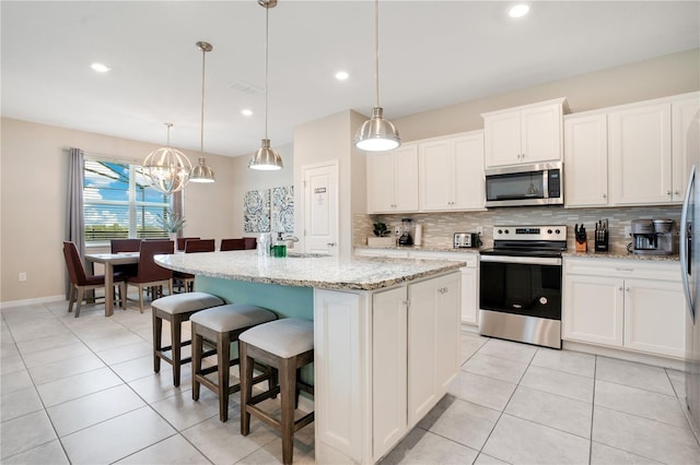 kitchen featuring a kitchen bar, light tile patterned floors, decorative backsplash, appliances with stainless steel finishes, and white cabinetry