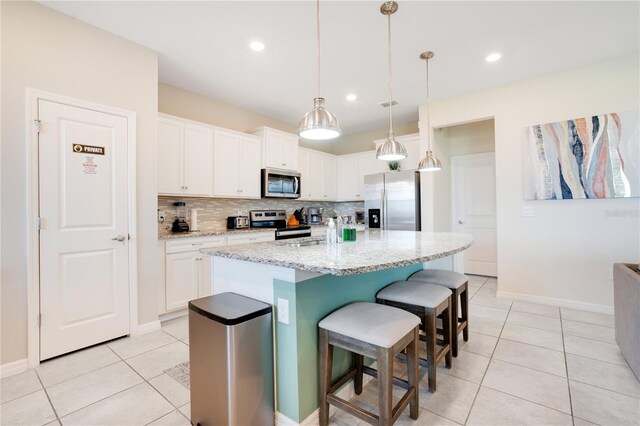 kitchen featuring light tile patterned floors, tasteful backsplash, appliances with stainless steel finishes, and white cabinetry