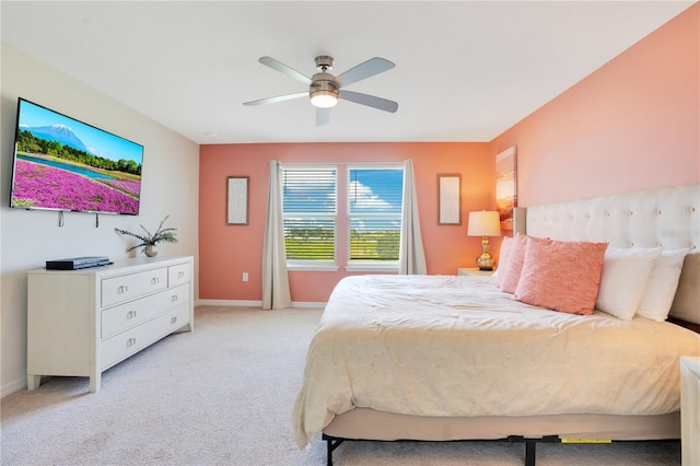 bedroom with a ceiling fan, baseboards, and light carpet