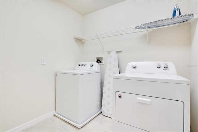 laundry room featuring baseboards, independent washer and dryer, light tile patterned flooring, and laundry area