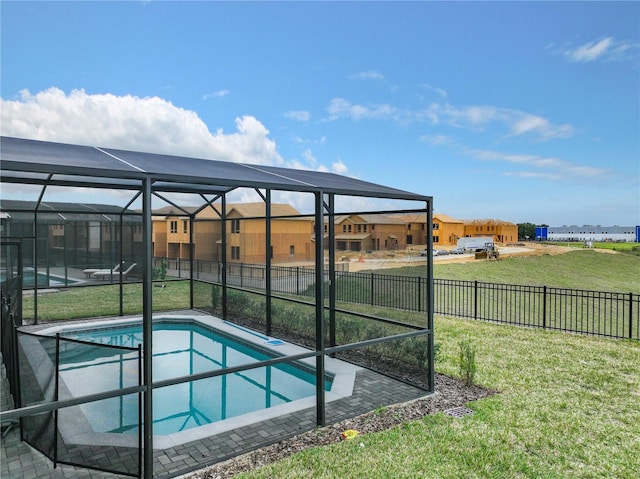 view of pool featuring glass enclosure, a fenced in pool, a fenced backyard, a lawn, and a residential view