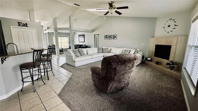 living area with visible vents, a fireplace, light tile patterned floors, lofted ceiling, and ceiling fan