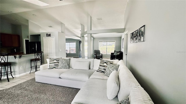 living area featuring vaulted ceiling, light tile patterned floors, and baseboards