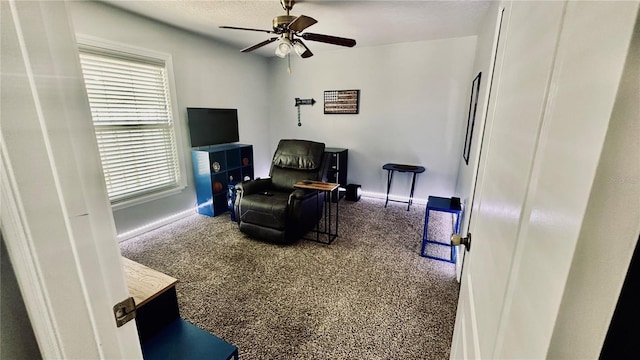 living area with baseboards and a ceiling fan