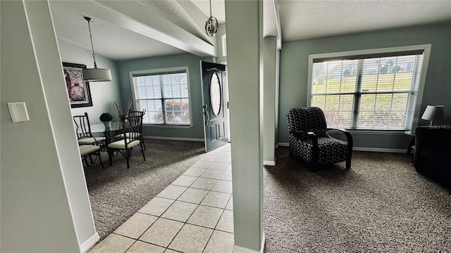 interior space featuring lofted ceiling, a textured ceiling, light tile patterned floors, baseboards, and light colored carpet