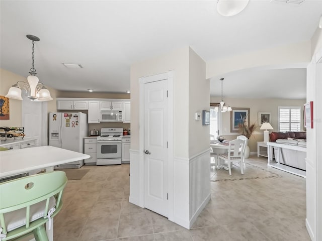 kitchen with hanging light fixtures, white appliances, a notable chandelier, and light countertops