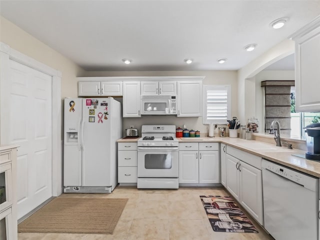 kitchen with white appliances, white cabinets, and a sink