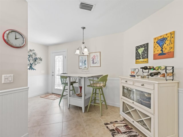 dining space featuring light tile patterned flooring, visible vents, a chandelier, and wainscoting