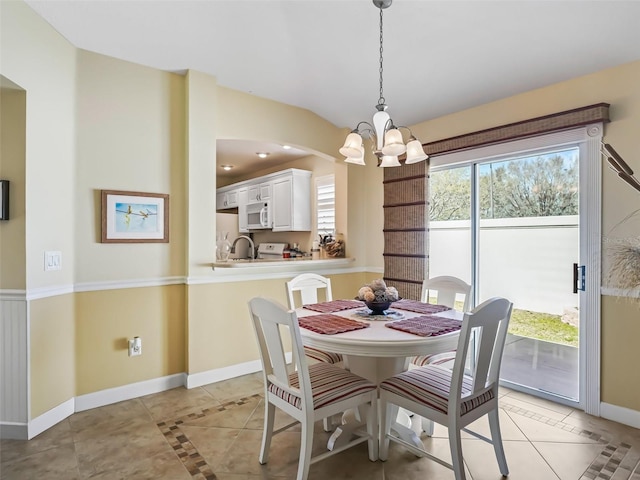 dining area with light tile patterned flooring, a notable chandelier, baseboards, and vaulted ceiling