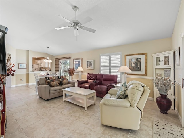 living area featuring a wealth of natural light, light tile patterned floors, ceiling fan with notable chandelier, and vaulted ceiling