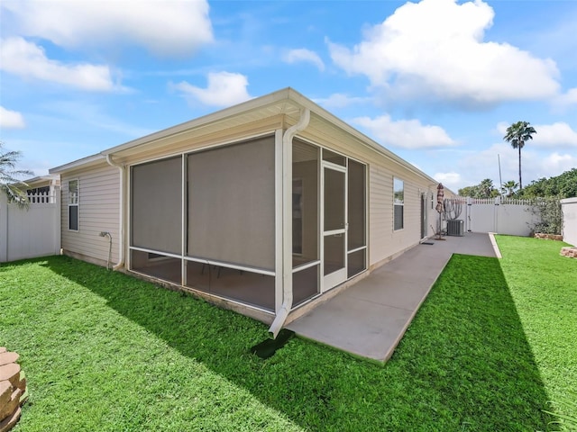 back of property with a yard, a sunroom, fence, and a gate