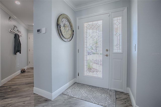 foyer entrance with baseboards, crown molding, and wood finished floors