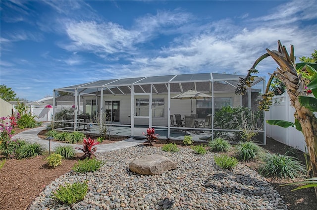 back of property featuring a fenced backyard, a lanai, and a patio