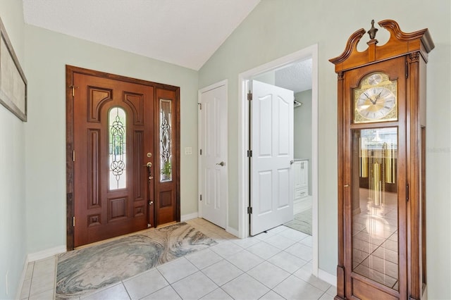 foyer featuring vaulted ceiling, light tile patterned floors, and a healthy amount of sunlight