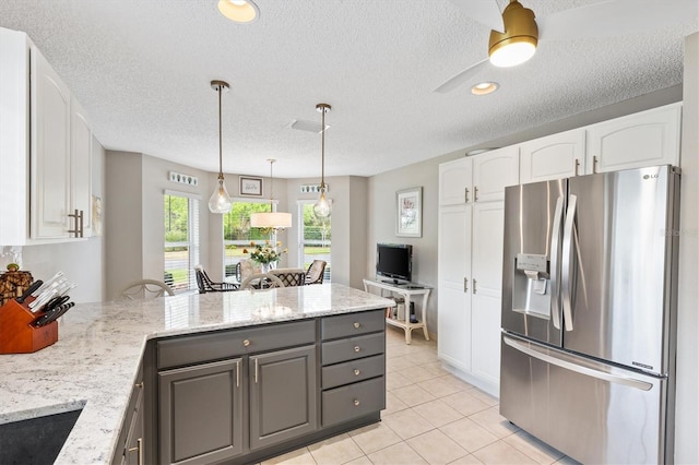 kitchen featuring light stone counters, a peninsula, light tile patterned flooring, white cabinets, and stainless steel fridge with ice dispenser