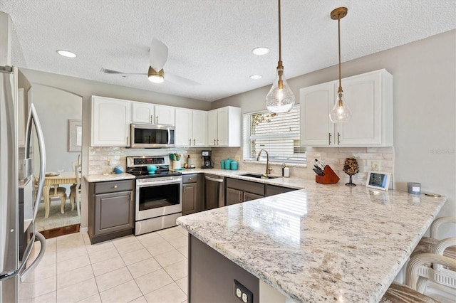 kitchen featuring white cabinetry, a peninsula, appliances with stainless steel finishes, and a sink