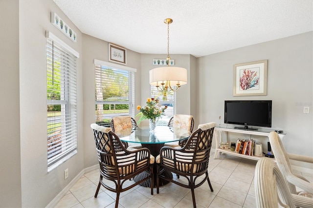 dining area featuring baseboards, a textured ceiling, an inviting chandelier, and light tile patterned flooring