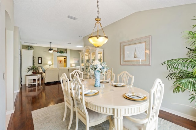 dining space with baseboards, dark wood-style flooring, arched walkways, ceiling fan, and vaulted ceiling