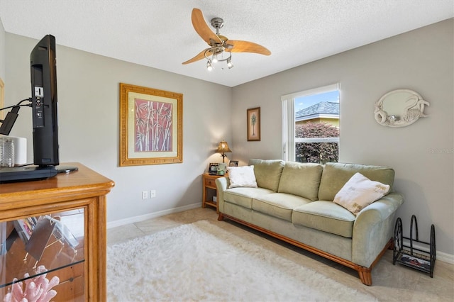 living room featuring baseboards, a textured ceiling, and ceiling fan