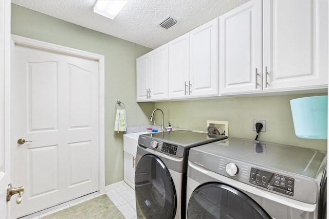 laundry area featuring visible vents, washer and clothes dryer, light tile patterned flooring, cabinet space, and a textured ceiling