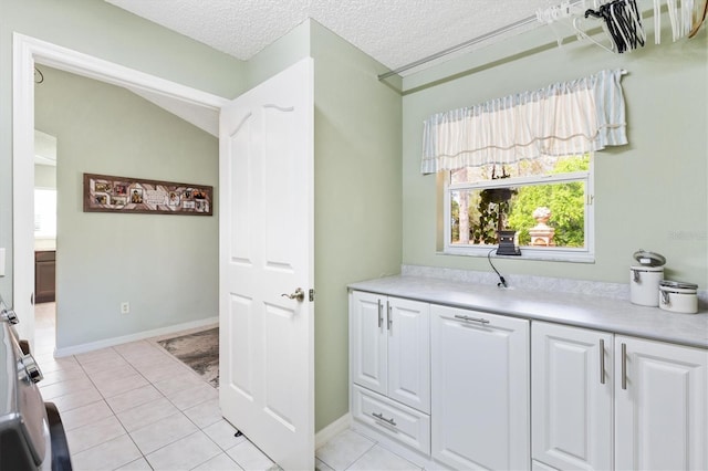 interior space with light tile patterned floors, baseboards, and a textured ceiling