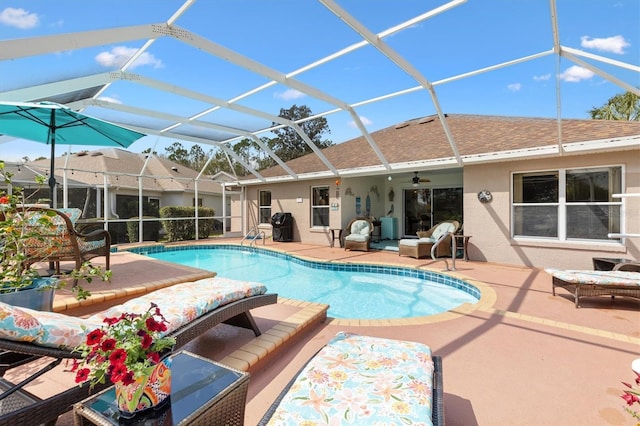 outdoor pool featuring glass enclosure, a patio area, and a ceiling fan