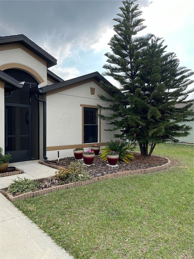 exterior space with stucco siding and a yard