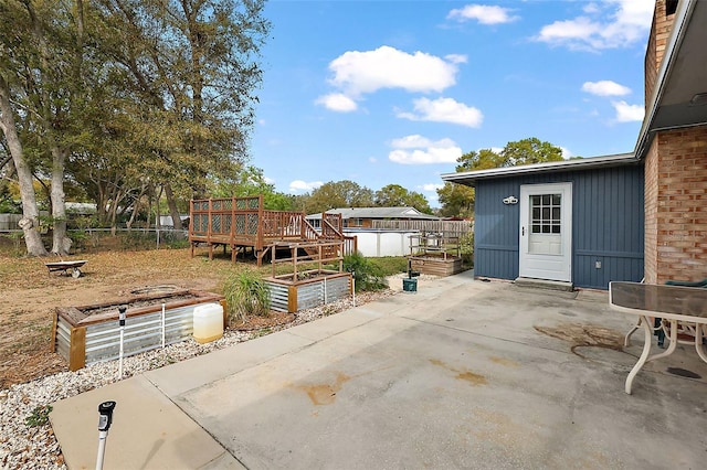 view of patio featuring a wooden deck, fence, and a garden