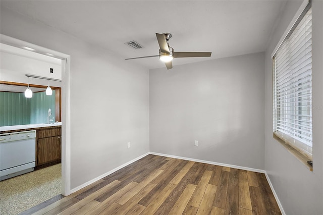 unfurnished room with visible vents, a sink, baseboards, and hardwood / wood-style flooring