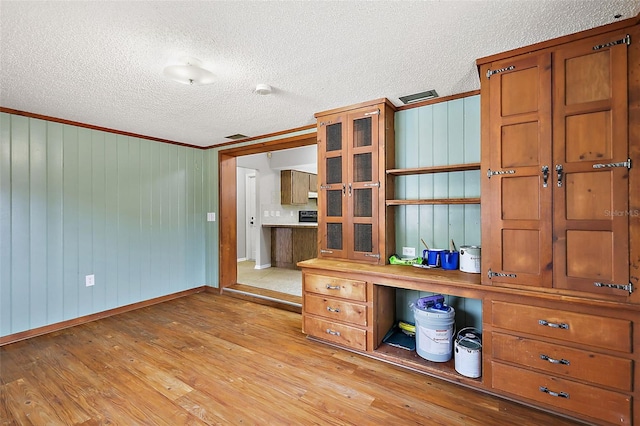 unfurnished office with light wood-type flooring, baseboards, a textured ceiling, and ornamental molding