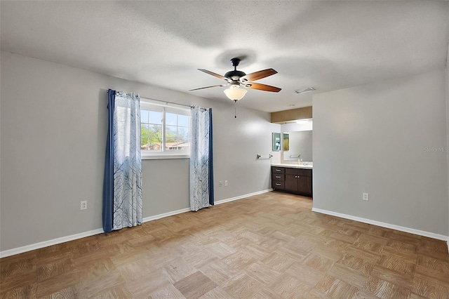 spare room with visible vents, a textured ceiling, baseboards, and a ceiling fan