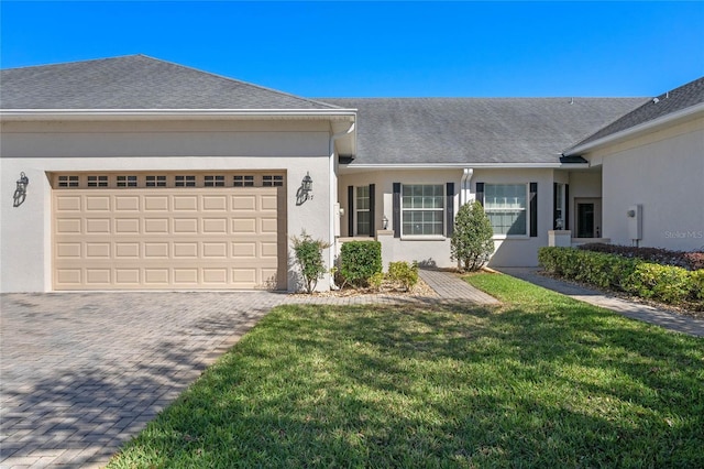 view of front of house featuring an attached garage, a shingled roof, stucco siding, a front lawn, and decorative driveway