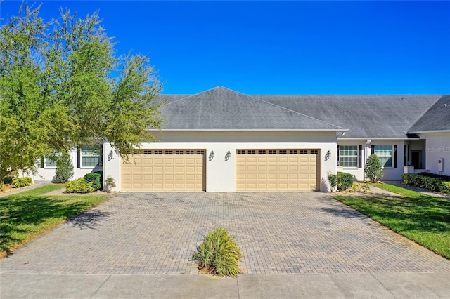 view of front facade featuring stucco siding, an attached garage, and decorative driveway