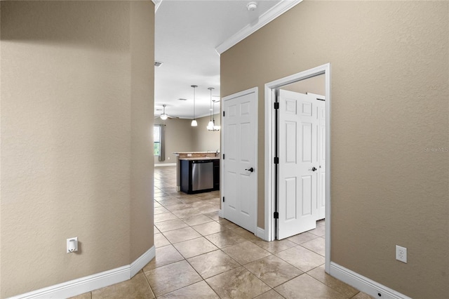 hallway with crown molding, light tile patterned floors, and baseboards