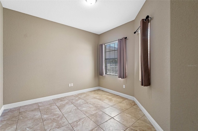 empty room with light tile patterned floors and baseboards