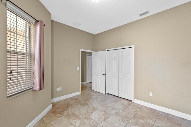 unfurnished bedroom with a closet, visible vents, and baseboards